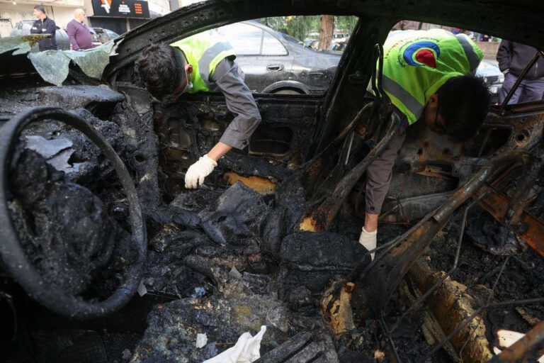 Civil defense members check a burnt car in the aftermath of what security sources said was an Israeli drone strike in Beirut.